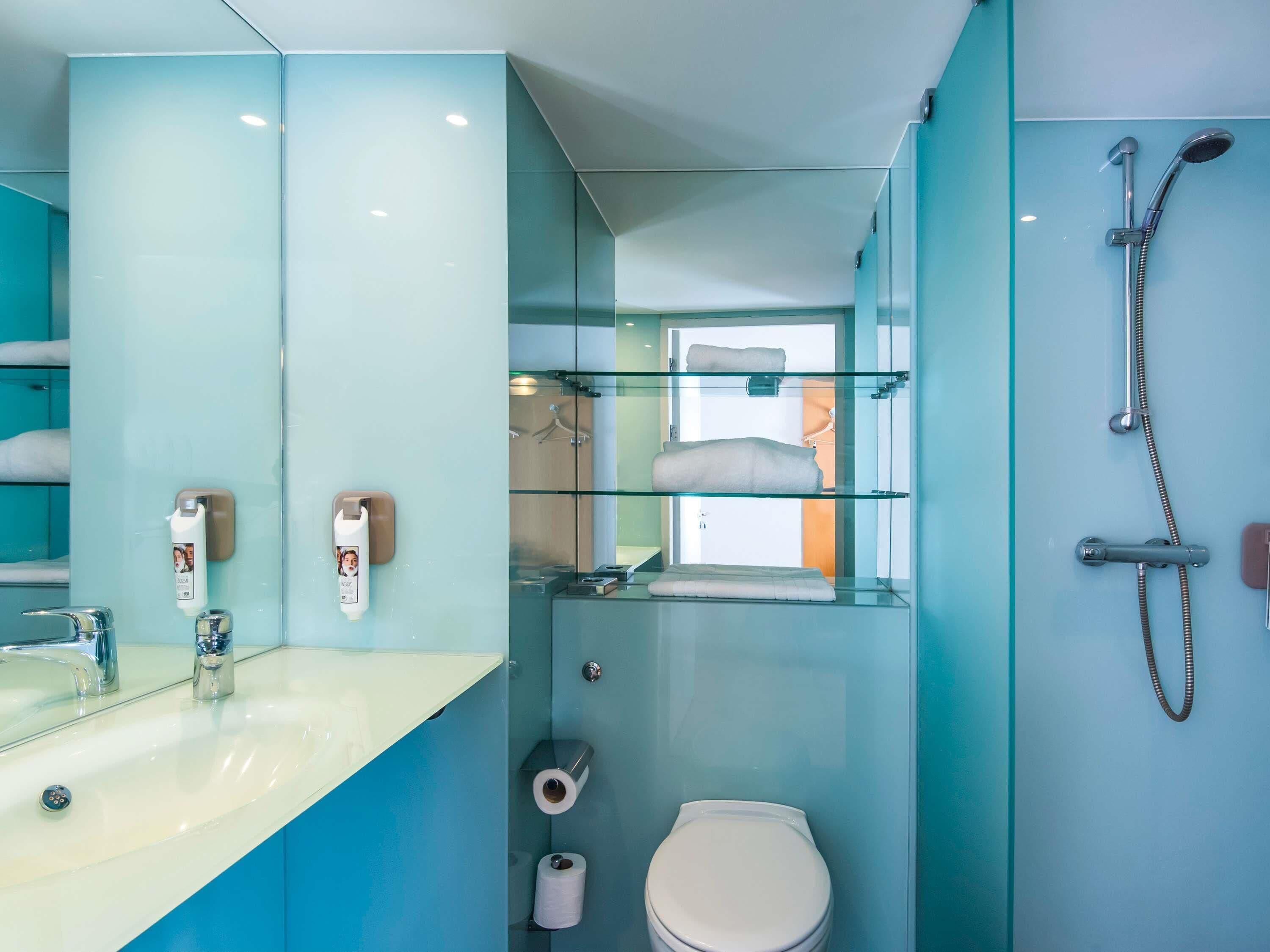 Une salle de bain moderne avec une douche à parois de verre, un lavabo avec un miroir et des toilettes.