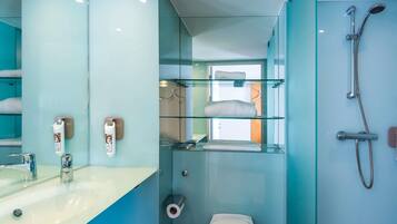 Une salle de bain moderne avec une douche à parois de verre, un lavabo avec un miroir et des toilettes.