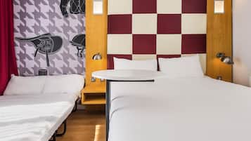 Habitación de hotel con dos camas individuales, una mesita redonda y un cabecero a cuadros.