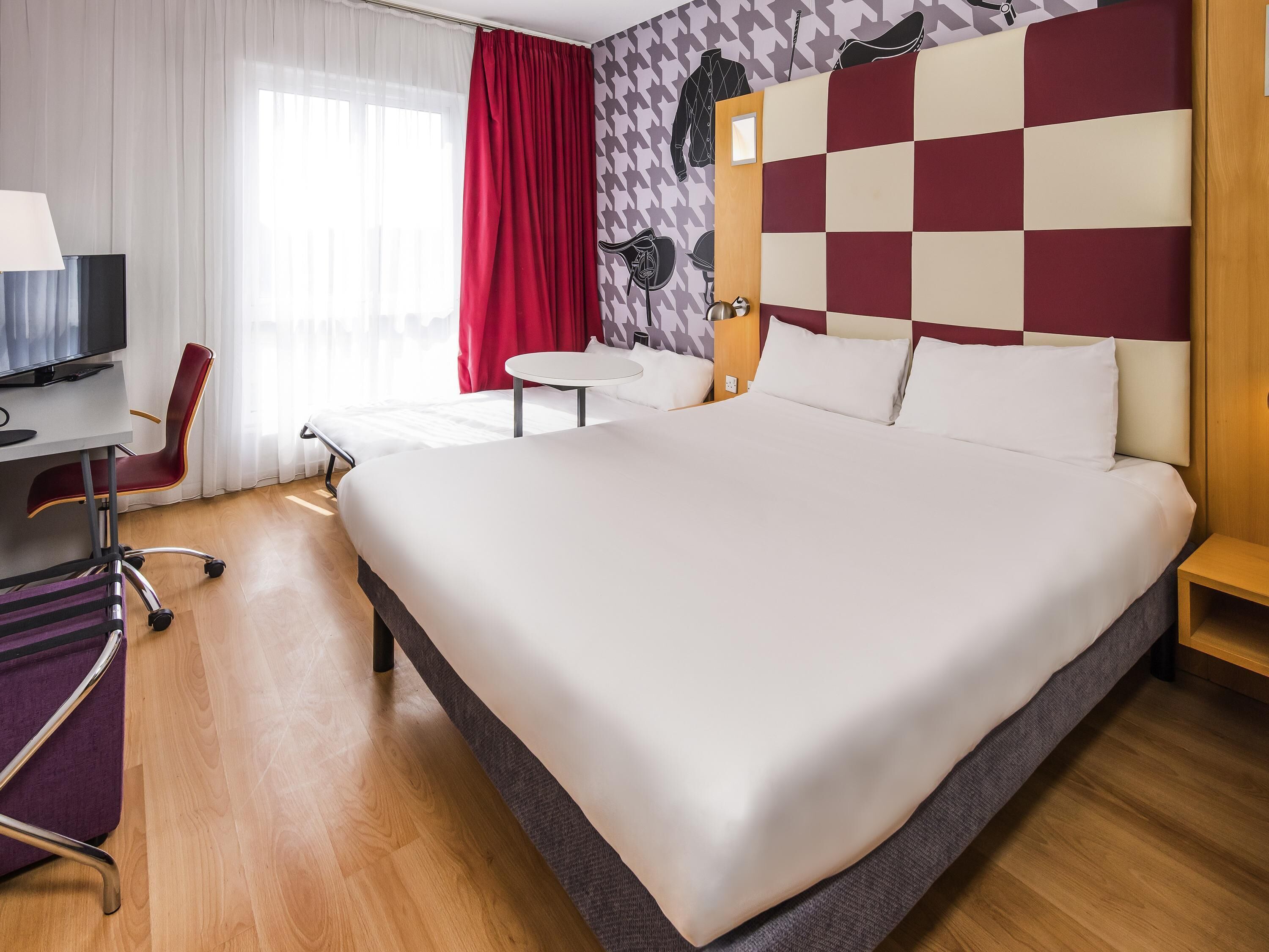 Une chambre d’hôtel avec un grand lit, un bureau avec une chaise, une télévision et une petite table avec une chaise.