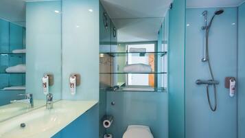 A modern bathroom with a glass shower enclosure, a sink with a mirror, and a toilet.