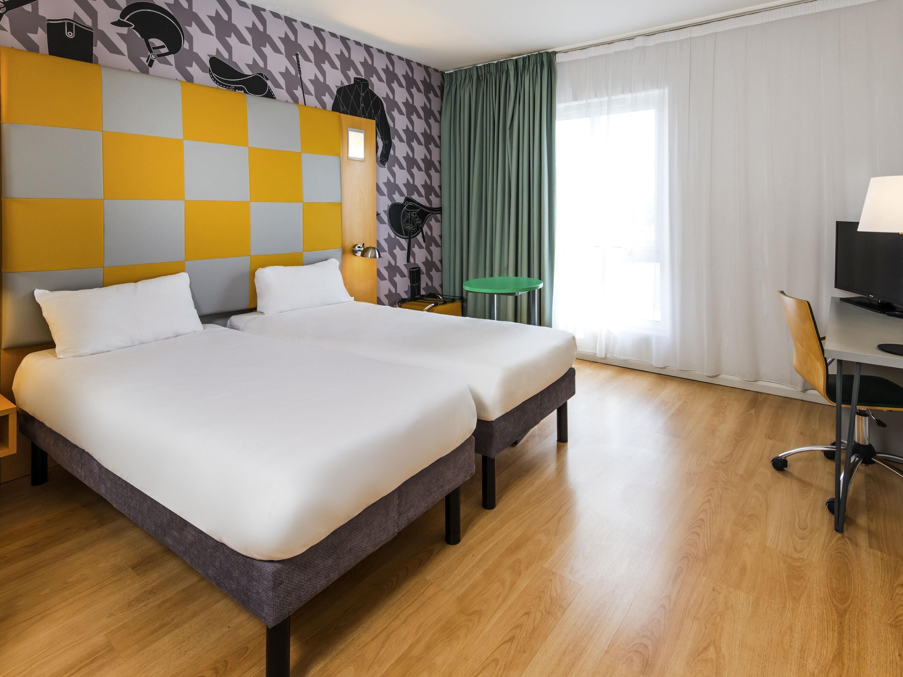 Une chambre d’hôtel avec un grand lit, un bureau avec une chaise, une petite table et un téléviseur.
