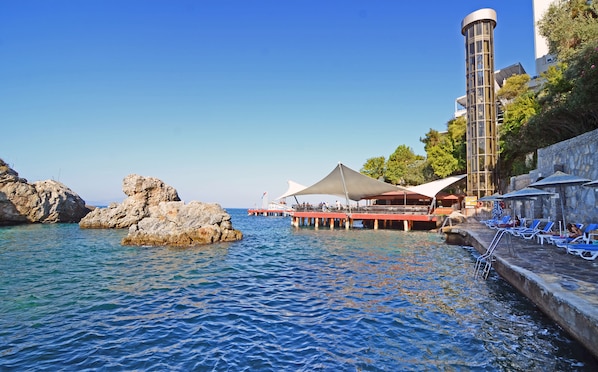 Private beach, sun-loungers, beach umbrellas, beach bar - Korumar Deluxe Hotel (Kusadasi)