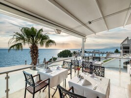Una terrazza con tavoli apparecchiati per mangiare, con vista su un lago e montagne.