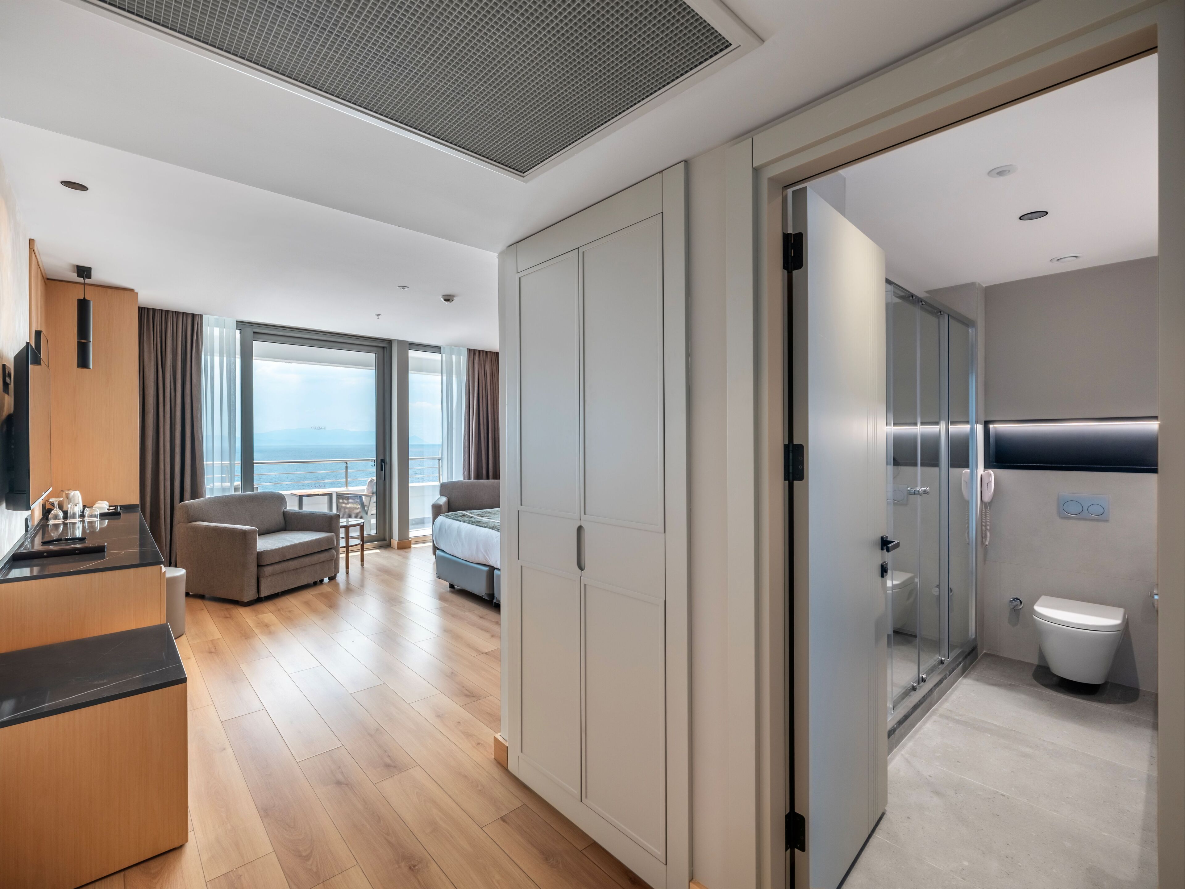 Una habitación de hotel moderna con balcón, kitchenette, cama y baño.