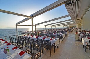 An outdoor dining area with tables and chairs, overlooking the sea.