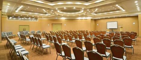 A conference room with rows of chairs, a whiteboard, and a projector screen.