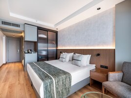 Camera d'albergo moderna con un letto grande, un comodino in legno, un tavolino da caffè in vetro e un'area salotto.