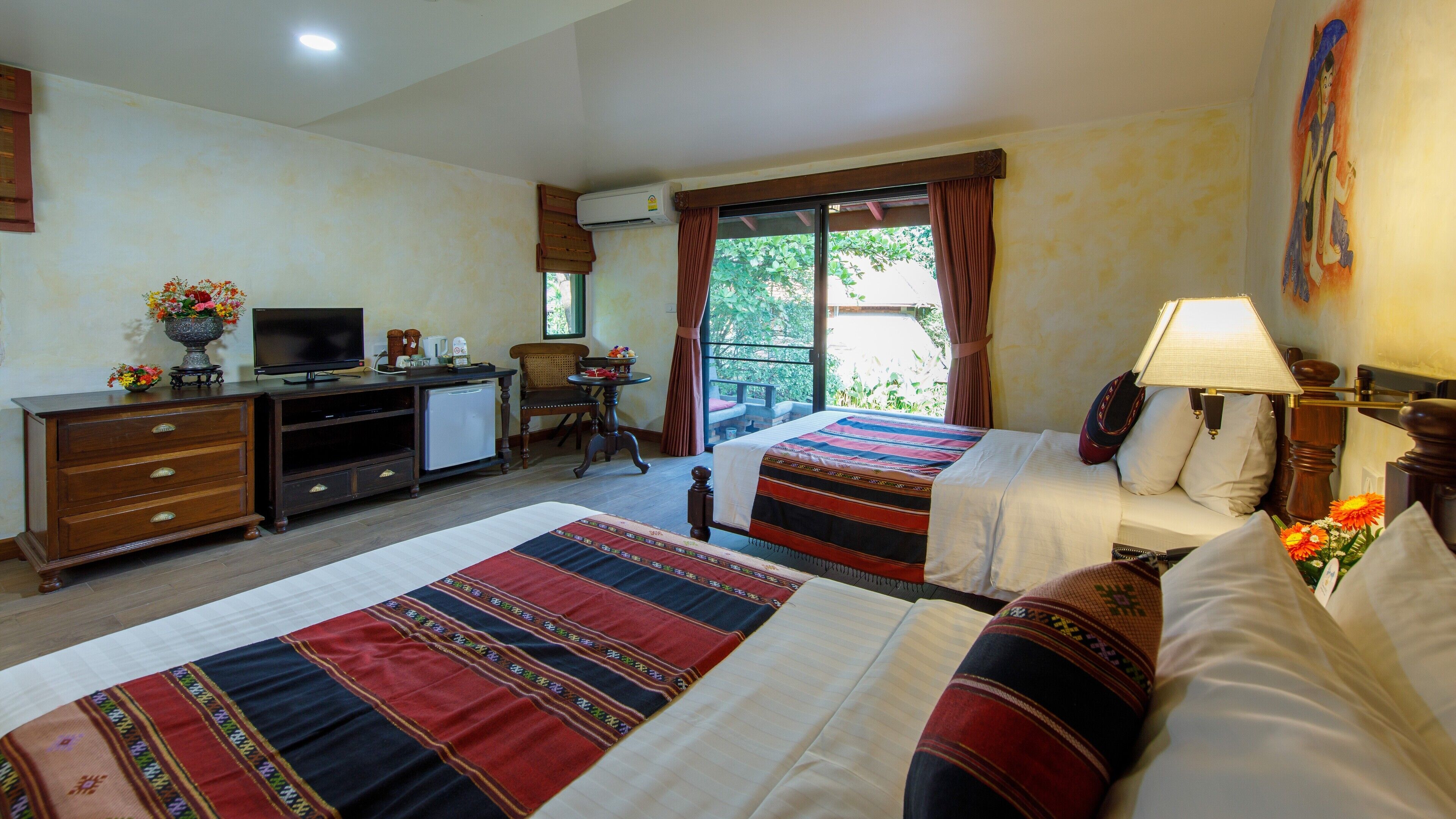 Une chambre d’hôtel avec deux lits, un bureau avec une télévision, un petit réfrigérateur et une fenêtre avec des rideaux.
