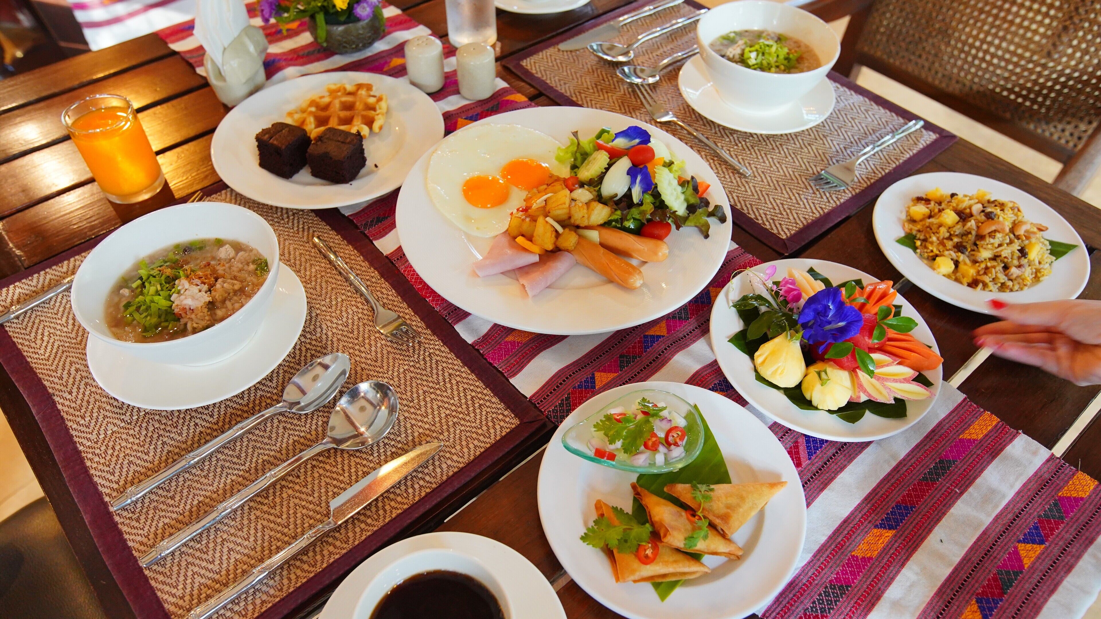 A table set with various dishes including waffles, eggs, soup, and a salad, indicating a breakfast buffet.