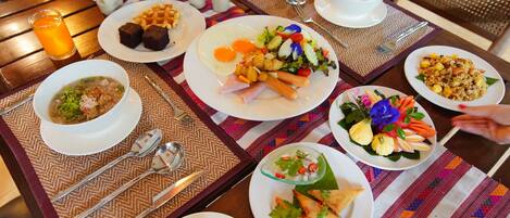 A table set with various dishes including waffles, eggs, soup, and a salad, indicating a breakfast buffet.