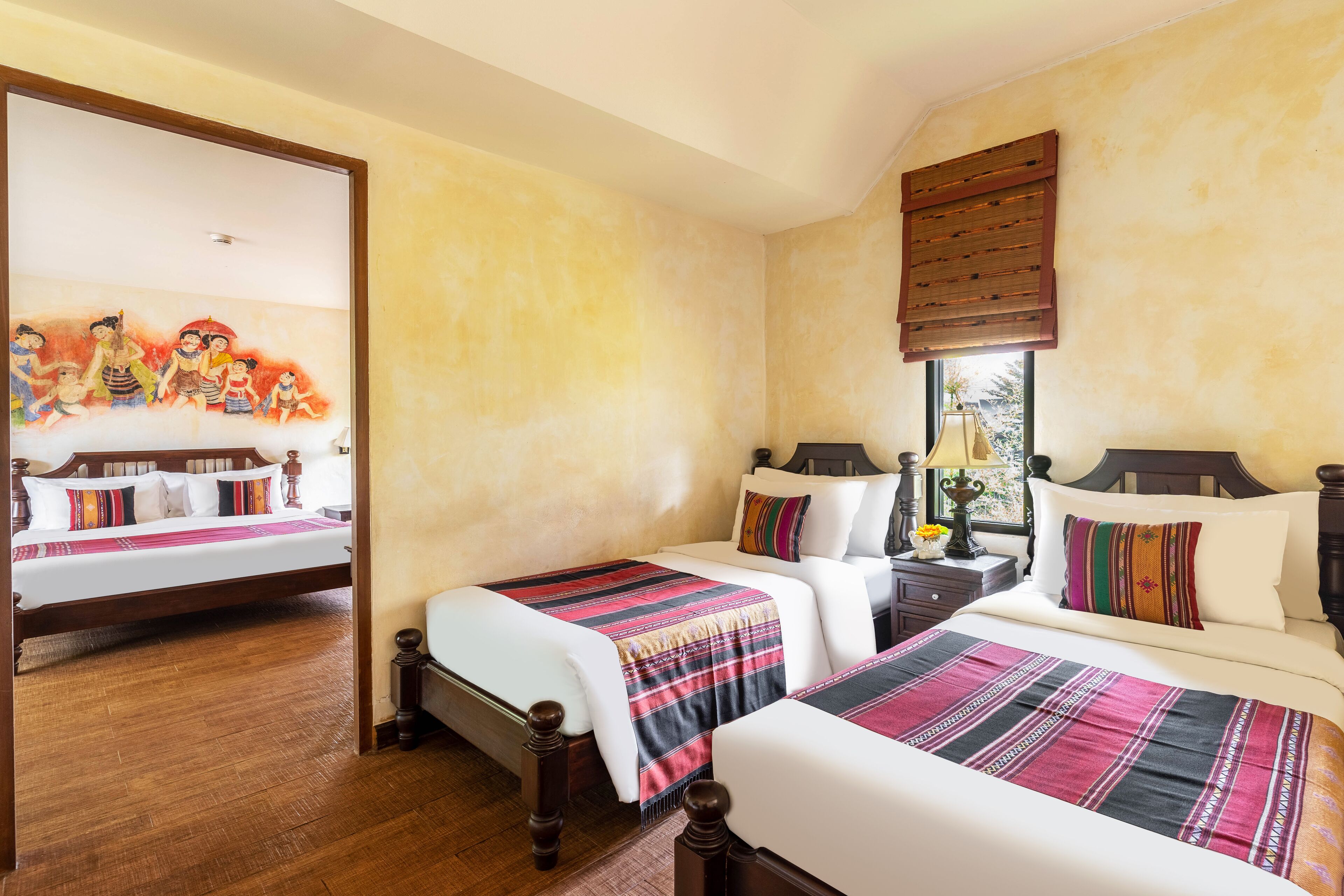 A hotel room with two beds, wooden headboards, and a large painting on the wall.