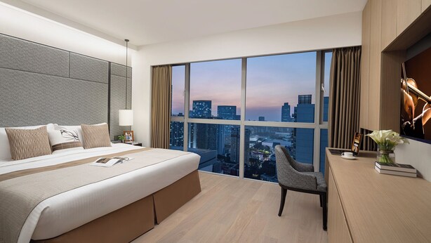 A modern hotel room with a large bed, a desk, and a chair. - Ascott Guangzhou (Guangzhou)