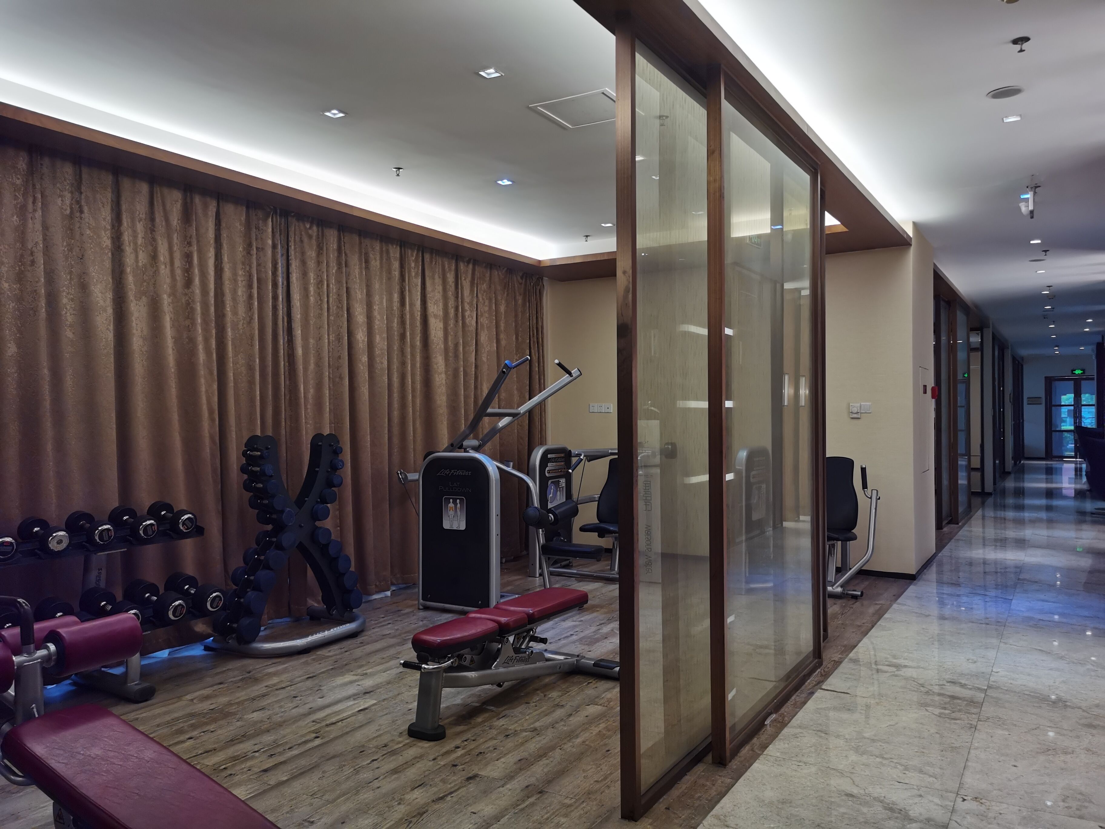 A gym with weightlifting equipment, a bench, and a mirrored wall.
