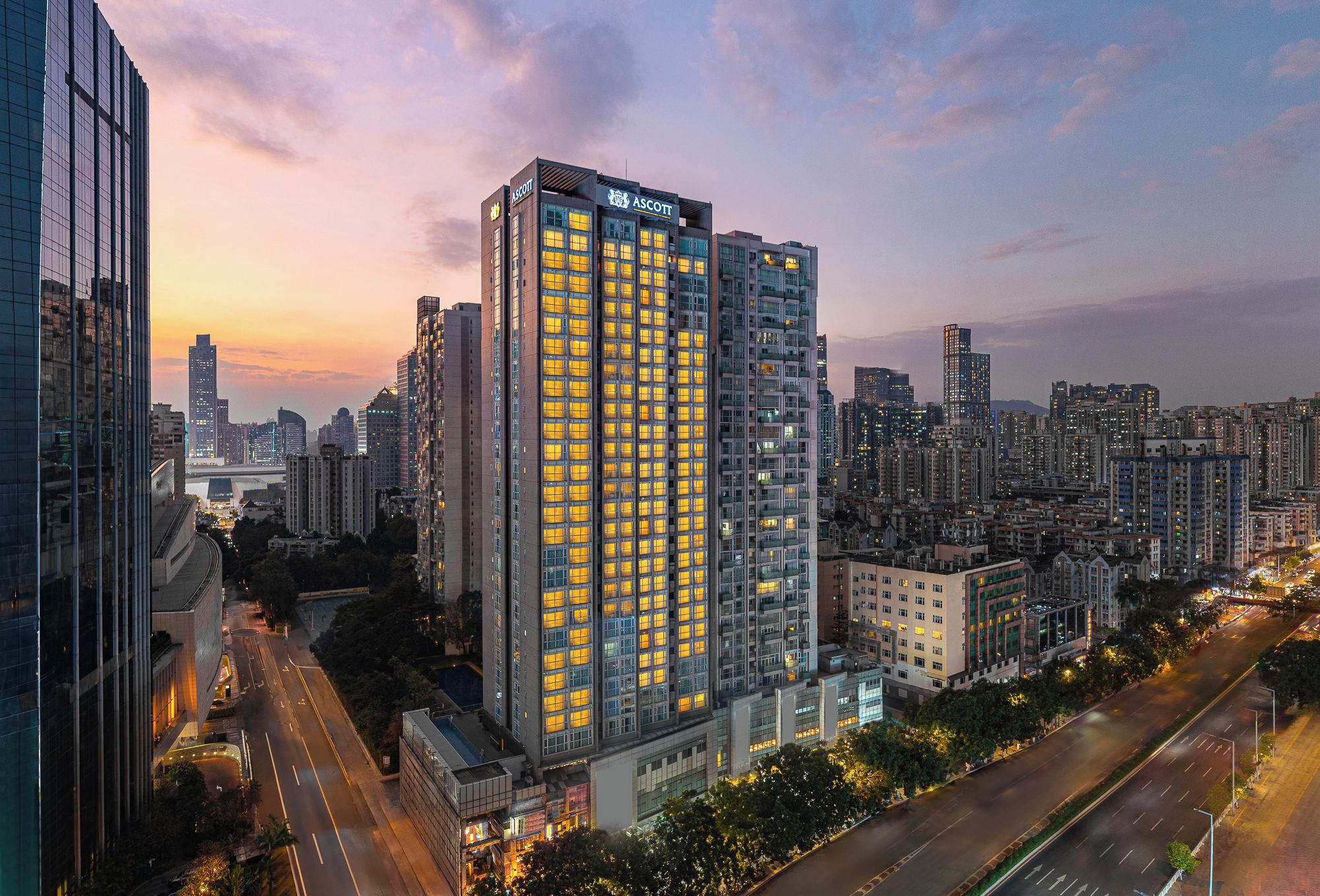 A high-rise hotel with multiple floors, surrounded by a cityscape at dusk.