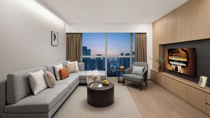 A modern living room with a sectional sofa, a round coffee table, a piano, and a large window with a city view. - Ascott Guangzhou (Guangzhou)