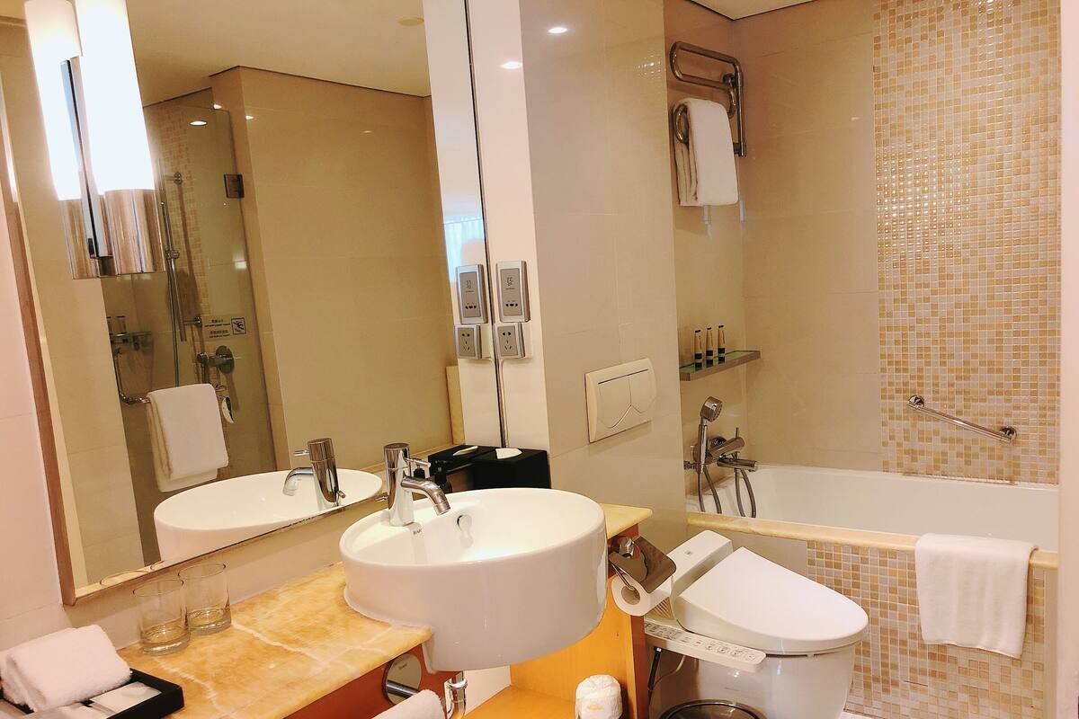 A modern bathroom with a sink, mirror, toilet, and shower.
