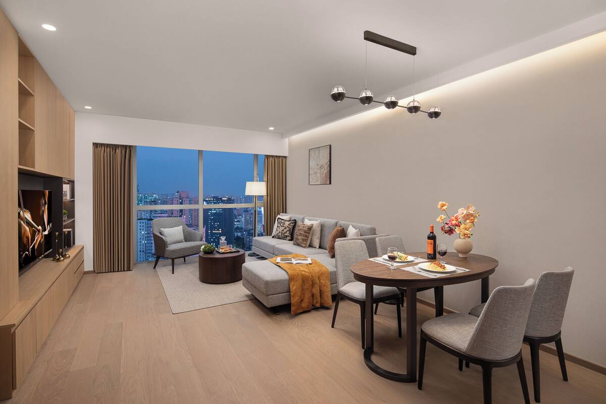 A modern living room with a sofa, coffee table, and dining table, a city view, and a television.
