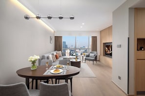 A modern living room with a dining area, a sofa set, a TV mounted on the wall, and a city view. - Ascott Guangzhou (Guangzhou)