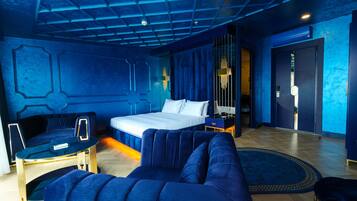 Ein modernes Hotelzimmer mit einem großen Bett, einem blauen Sofa, einem kleinen Tisch und einem dekorativen Teppich.