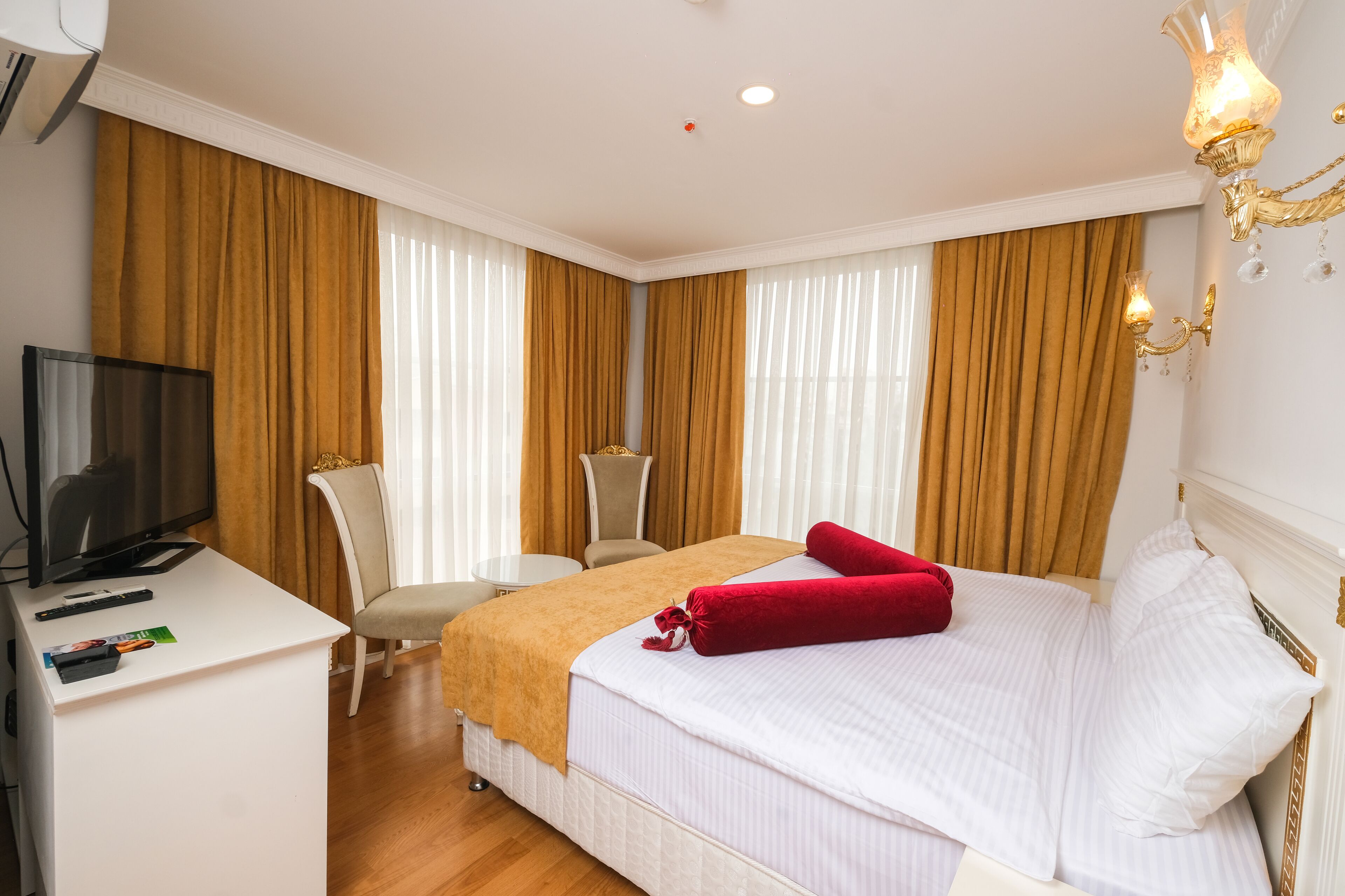 A hotel room with a bed, a desk with a television, and a chair.
