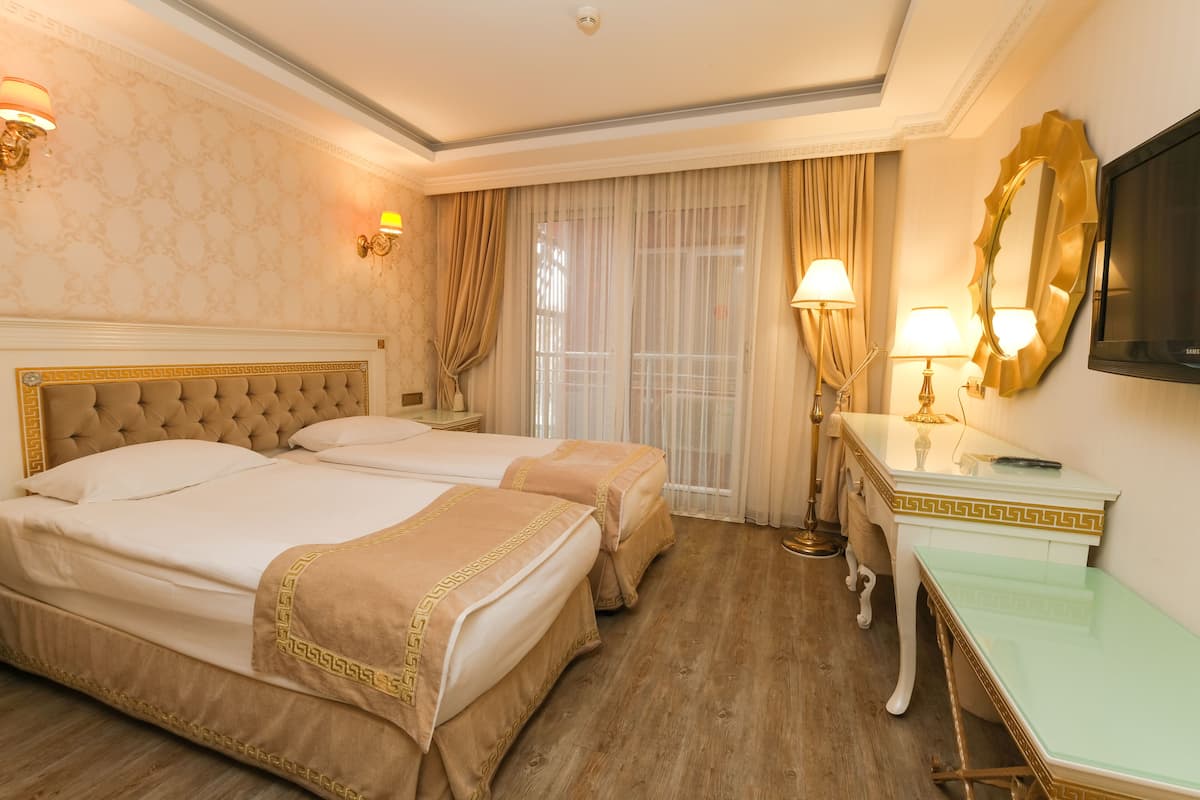 Habitación de hotel con dos camas, un escritorio, un televisor y un espejo grande.