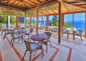 An outdoor patio with wicker furniture and large windows overlooking a scenic view.