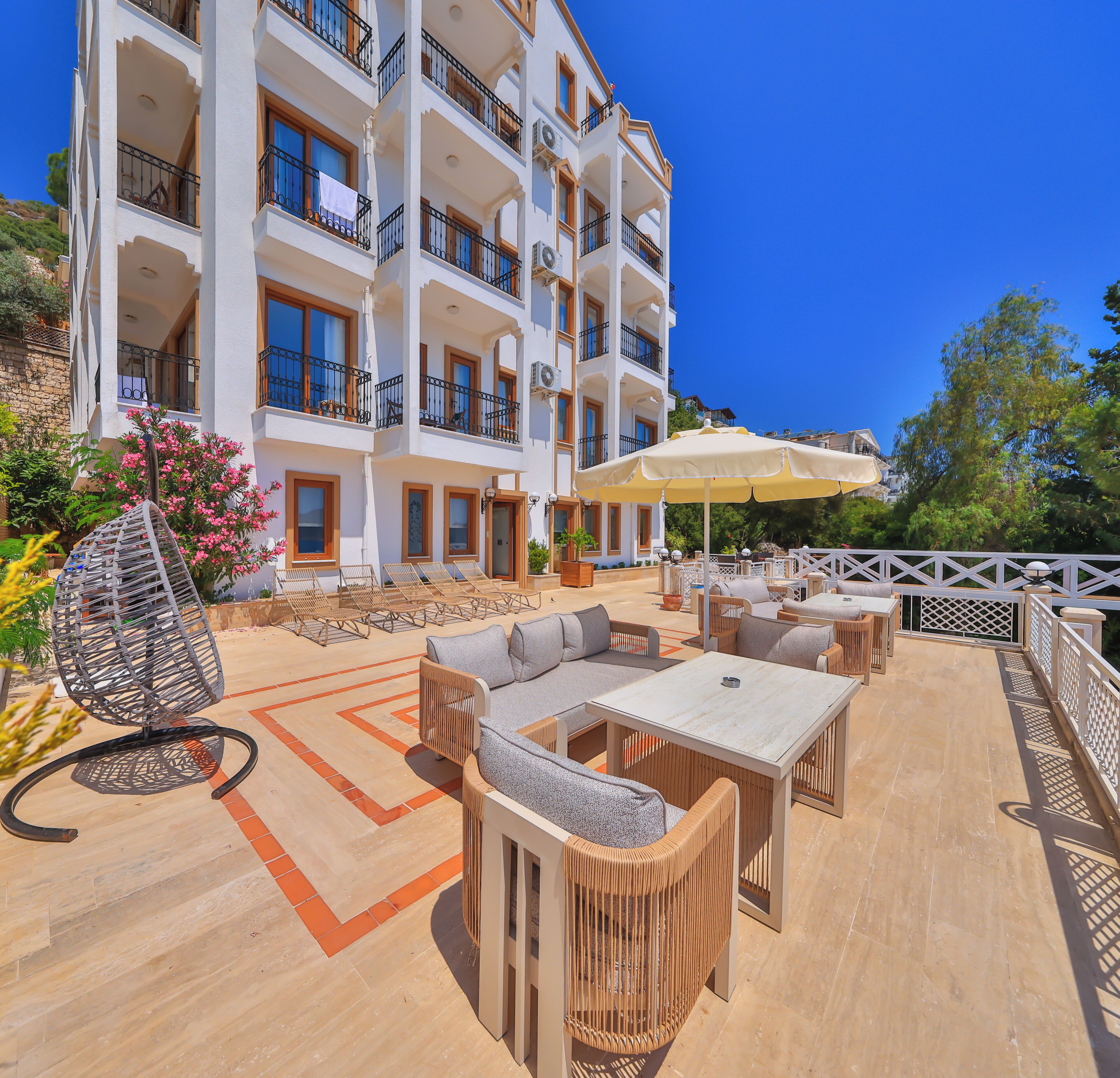 A multi-story hotel with outdoor seating, a pool, and a view of the surrounding landscape.