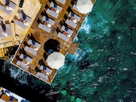 An aerial view of a floating hotel with multiple deck levels, outdoor seating areas, and a view of the surrounding water.