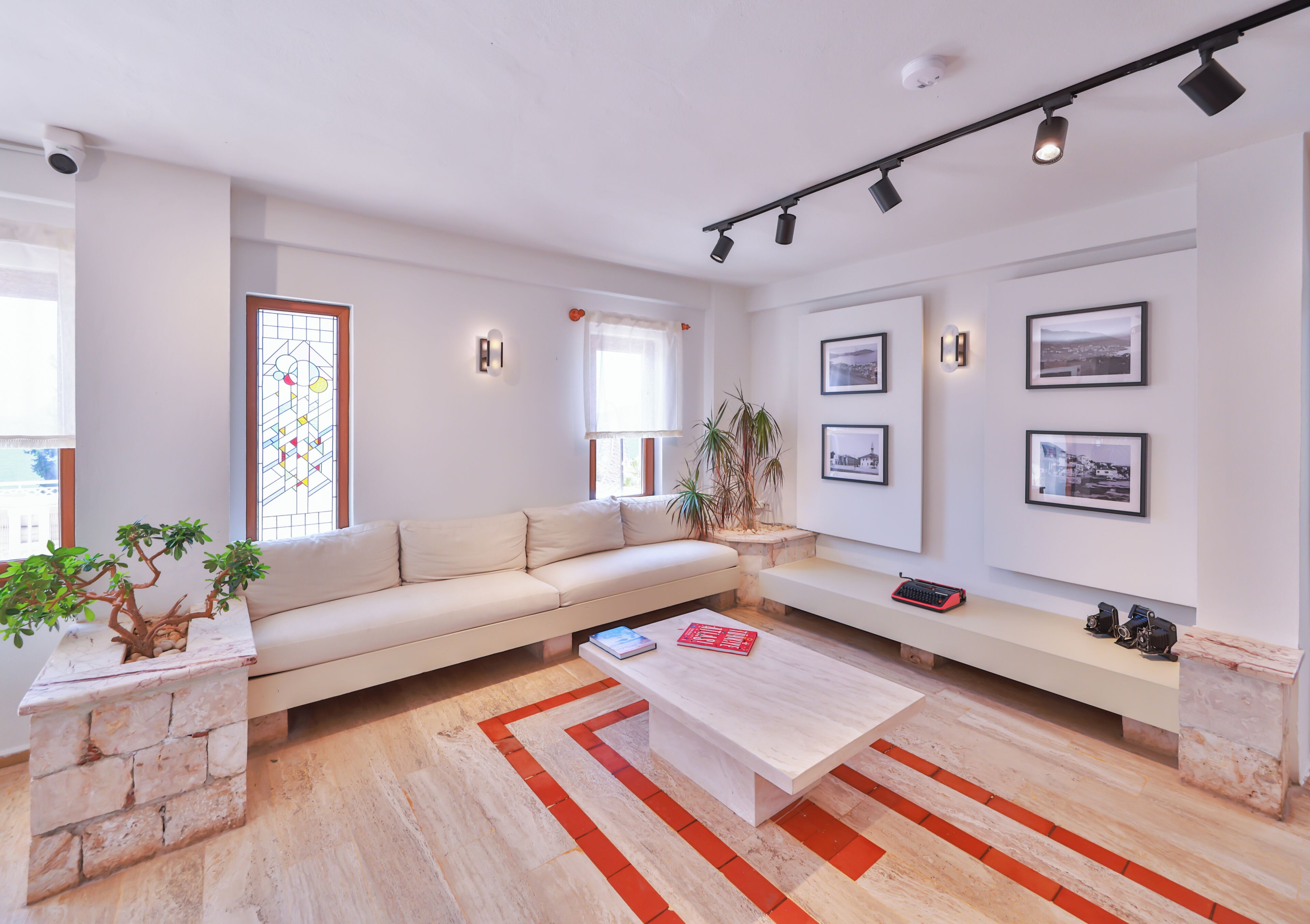 Ein modernes Wohnzimmer mit einer Couch, einem Couchtisch, einer Bank und einer Wand mit gerahmten Bildern.