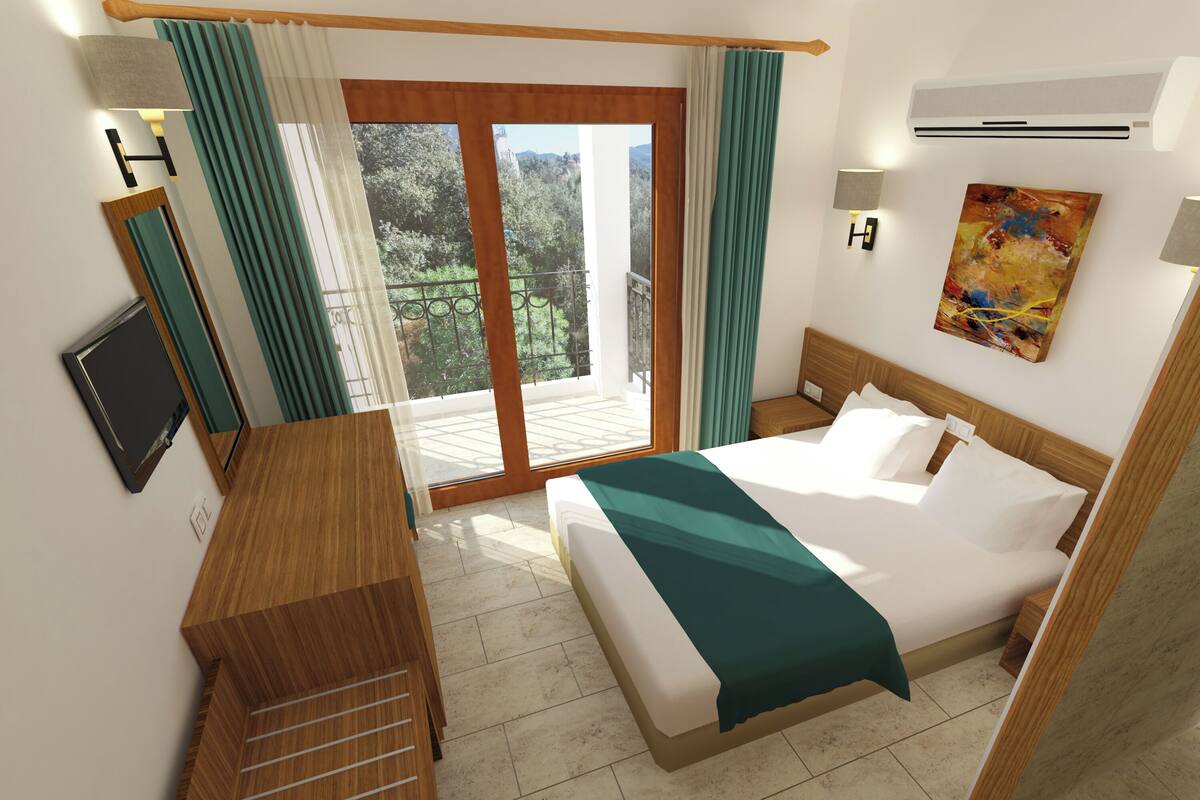 A hotel room with a bed, a desk, a TV, a painting, and a view of greenery through the window.
