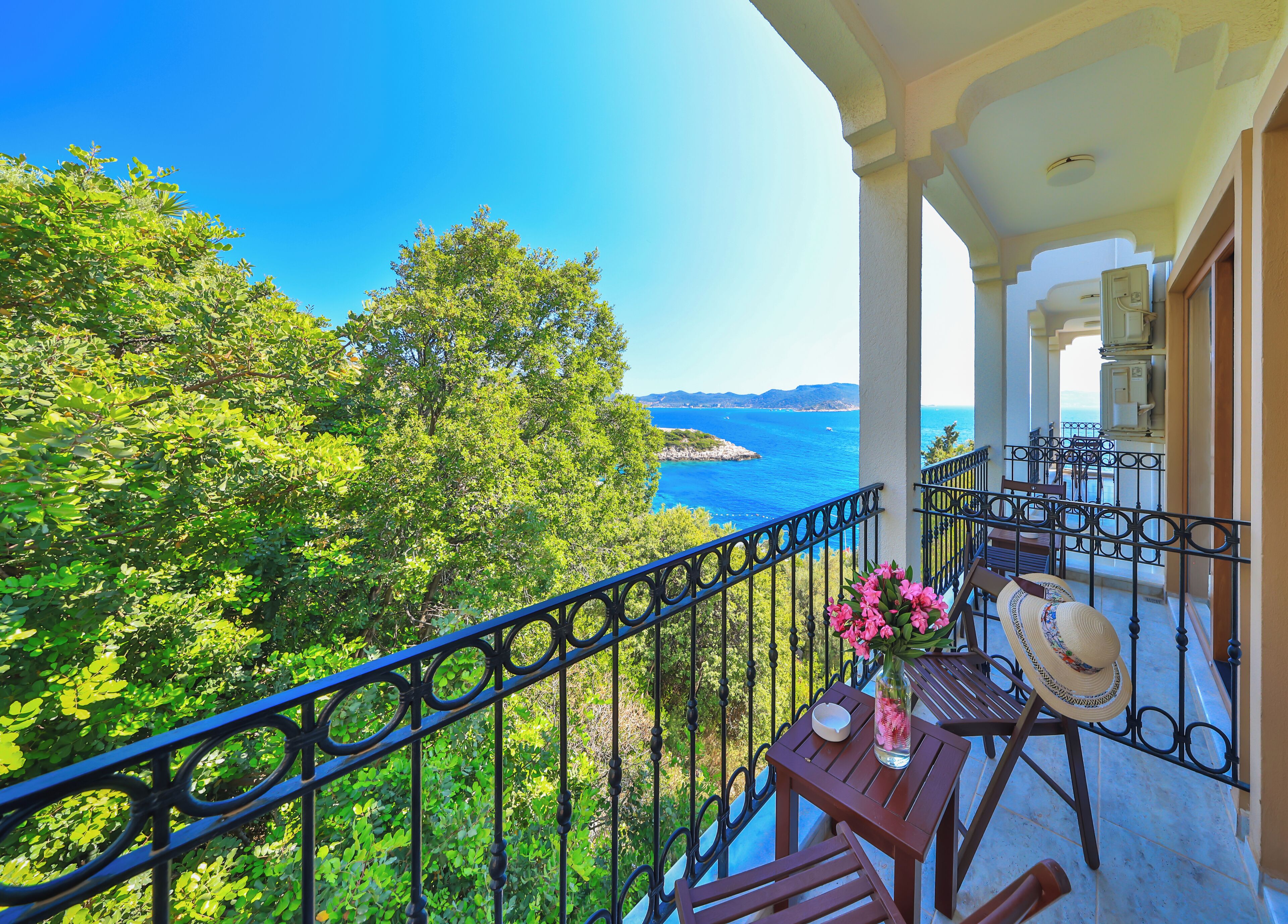 Un balcón con vista al mar, una mesa con un florero y una silla.