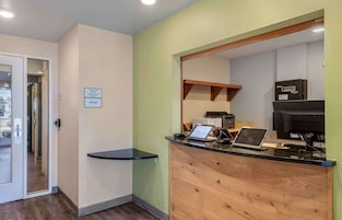 A reception area with a check-in/check-out counter, a laptop, a printer, and a sign indicating office space.