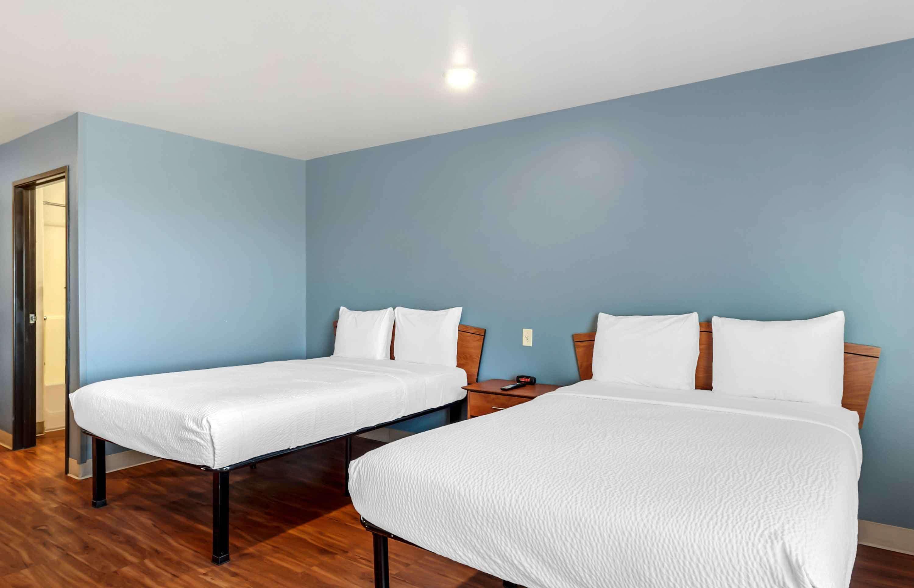 Habitació d'hotel amb dos llits, terres de fusta i parets de blau clar.