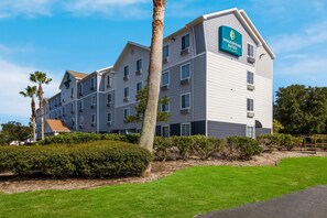 A multi-story hotel with a sign for 'Woodspring Suites' on the facade.