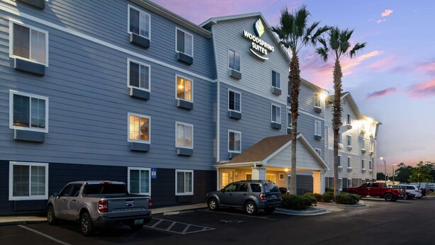 A hotel with multiple floors, a parking lot, and a sign indicating it is a Woodspring Suites. - WoodSpring Suites Jacksonville East 295 Cruise Port (Jacksonville)