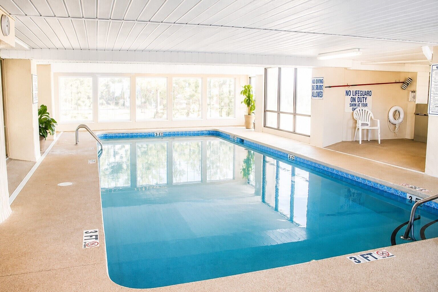 Une piscine intérieure dotée d’une signalisation claire, d’un poste de surveillance pour les maîtres-nageurs et offrant une vue sur l’extérieur grâce à de grandes fenêtres.