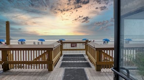A wooden deck with a view of the beach and ocean.