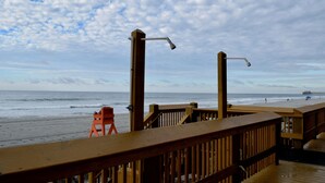 A wooden deck with railings overlooking a beach.