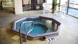 Een hottub met een metalen trap, omgeven door een betonnen vloer. Er staan borden met een maximale diepte van 3 voet.