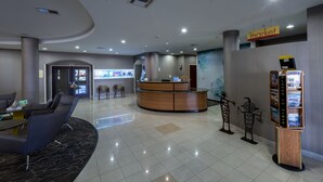 A reception area with a curved reception desk, seating area with chairs, and a 'market' sign. - Springhill Suites by Marriott Ridgecrest (Ridgecrest)