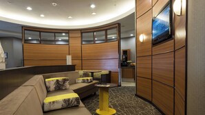 A modern lobby with a curved seating area, a small table, and a television mounted on the wall. - Springhill Suites by Marriott Ridgecrest (Ridgecrest)