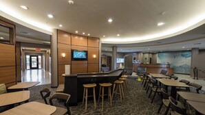 A modern hotel lobby with a curved reception desk, bar stools, and a seating area with tables and chairs. - Springhill Suites by Marriott Ridgecrest (Ridgecrest)