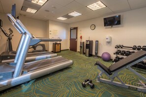 A fitness center with treadmills, a bench press, dumbbells, and a stationary bike.