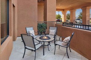 Un patio al aire libre con cuatro sillas y una mesa redonda, que incluye un hogar para fuego empotrado.