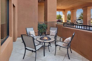 Un patio al aire libre con cuatro sillas y una mesa redonda, que incluye un hogar para fuego empotrado.