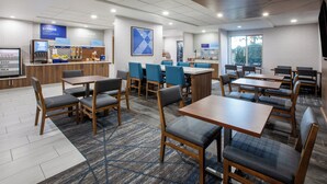 A hotel breakfast area with seating, a coffee machine, and a fruit display. - Holiday Inn Express & Suites Lathrop by IHG (Lathrop)