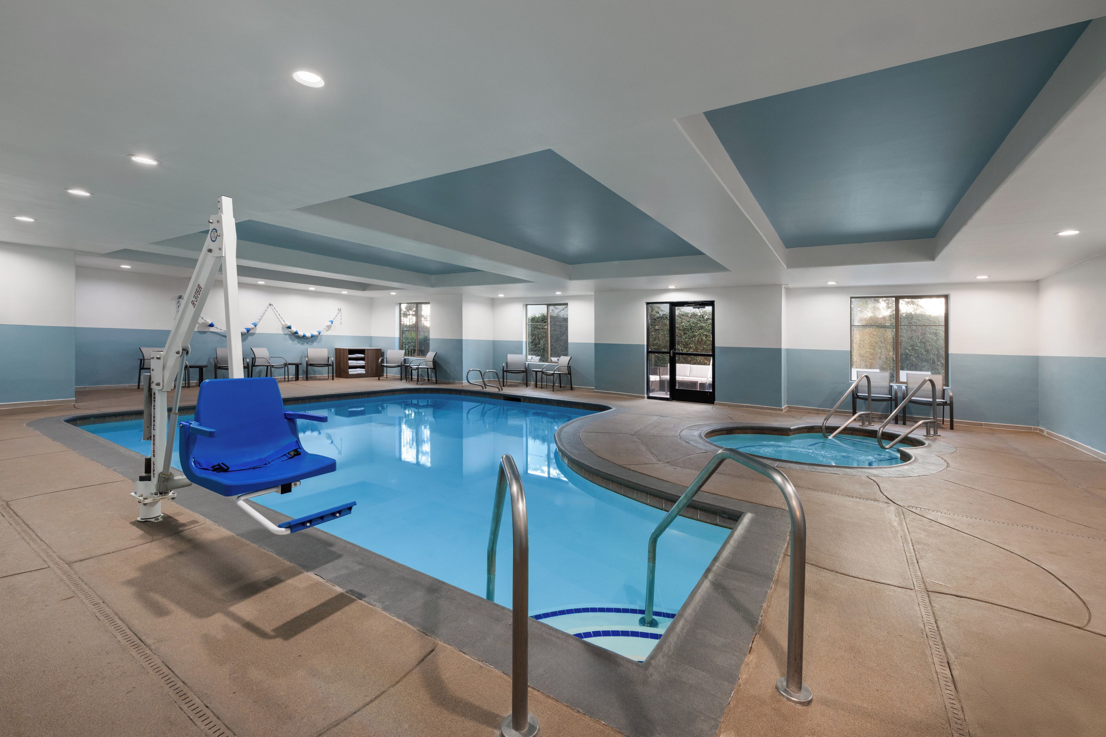 An indoor swimming pool with a blue chair, a lifeguard stand, and a separate smaller pool area.