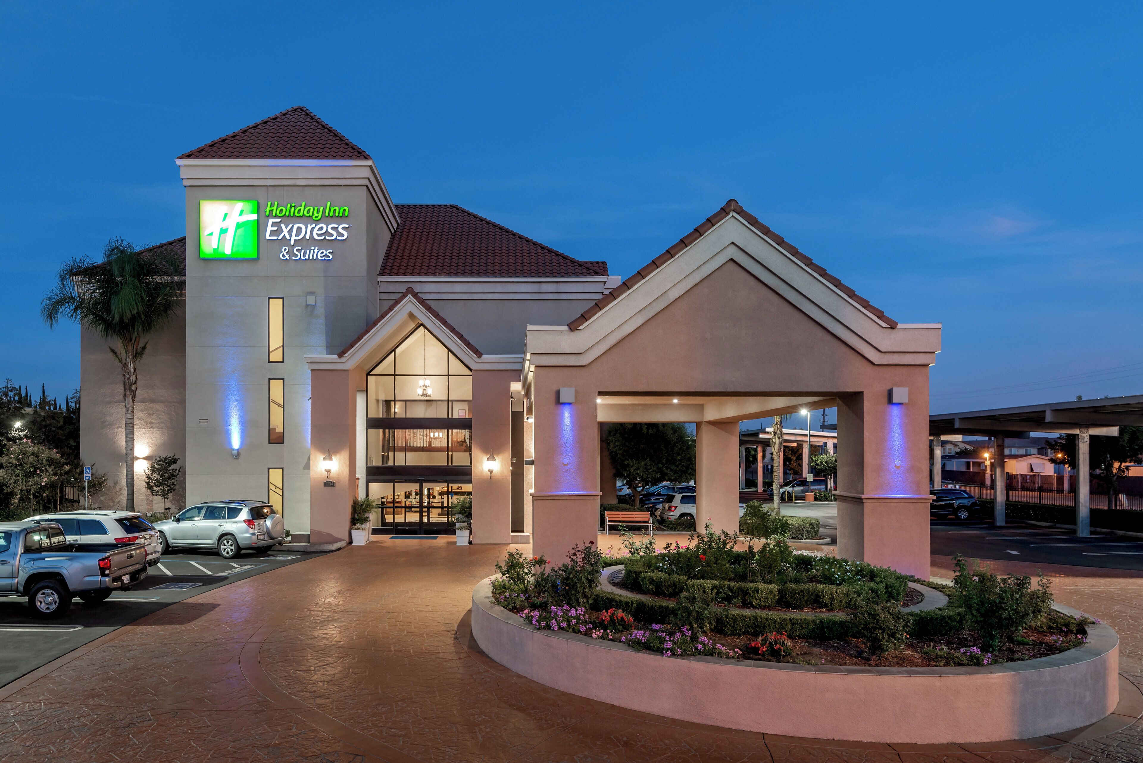 A Holiday Inn Express & Suites hotel with a parking lot, entrance, and landscaped garden.
