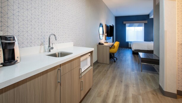 A modern hotel room with a kitchenette, a bed, a desk, and a bathroom. - Holiday Inn Express & Suites Lathrop by IHG (Lathrop)